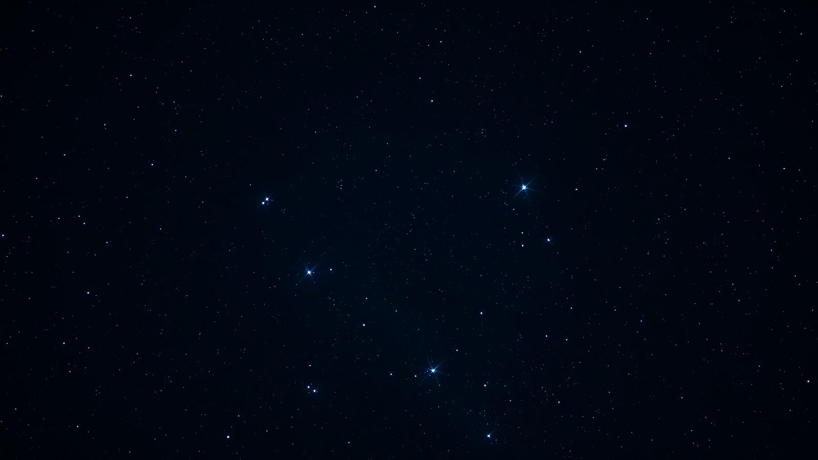 The Pleiades star cluster showing bright blue-white stars in dark space