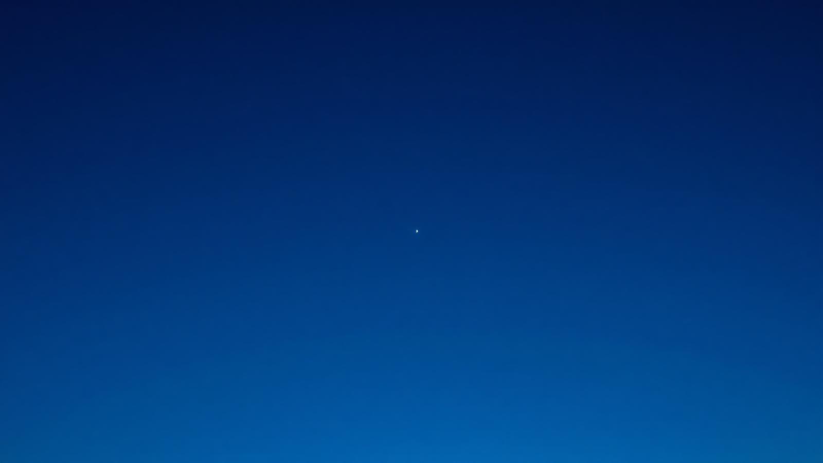A deep blue twilight sky with a bright satellite dot near zenith