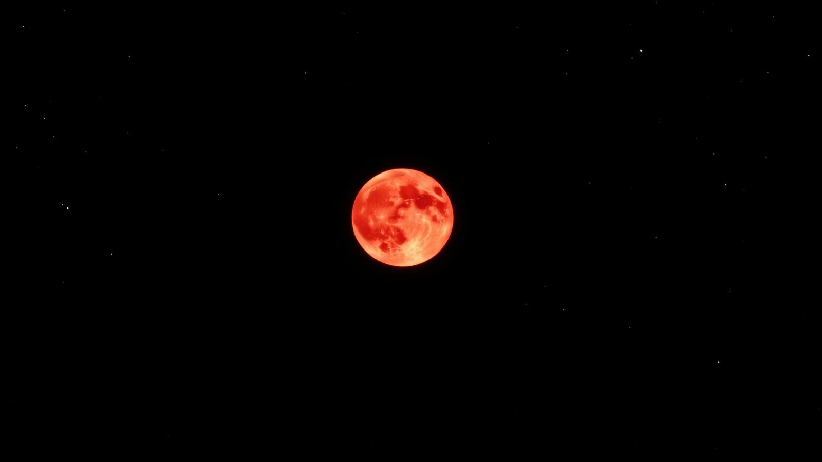 A deep red total lunar eclipse Moon in a starry sky