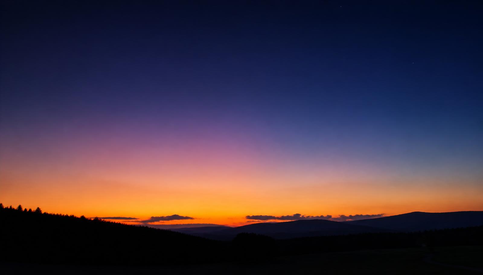 Wide sky gradient from warm sunset through blue hour to deep indigo twilight