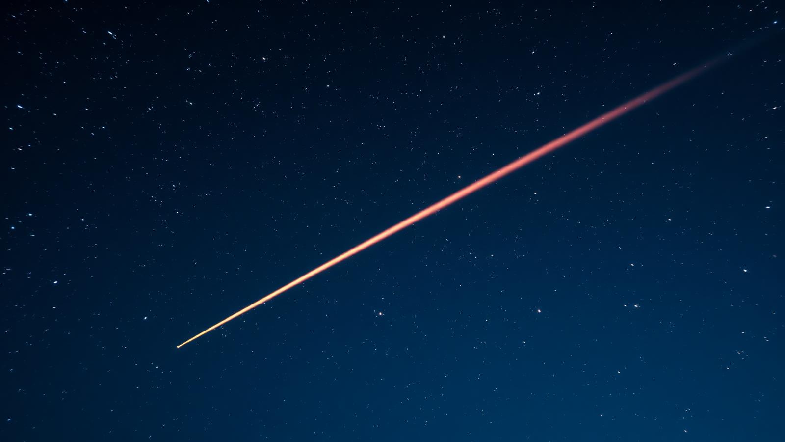 A bright, colourful Geminid fireball crossing a starry sky